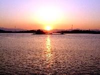 オレンジ色に輝く夕日が海に沈んでいく二子島の夕陽の写真