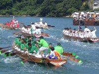 海の上に漕ぎ手の乗った和船が速さを競っている櫂伝馬競漕が行われている「ひがしの住吉祭」の写真