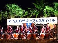 舞台の上に沢山の和太鼓が並んでおり、演奏者が法被を着て和太鼓の演奏をしている大崎上島サマーフェスティバルの写真