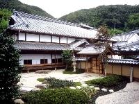 海と島の歴史資料館（大望月邸）の外観と、石灯篭があり庭石や草木がきれいな日本庭園が写っている写真